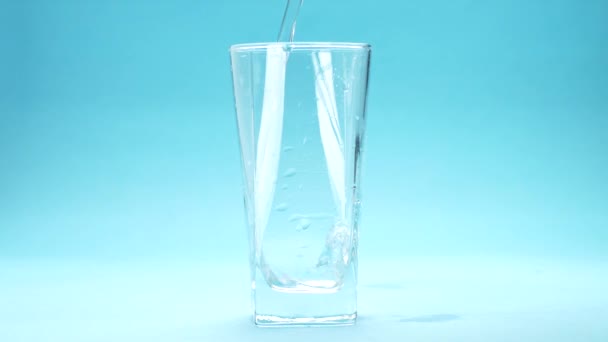 Agua Vierte Vaso Sobre Fondo Azul — Vídeos de Stock