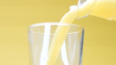 Portakal suyu sarı arkaplanda bir bardağa dökülür.