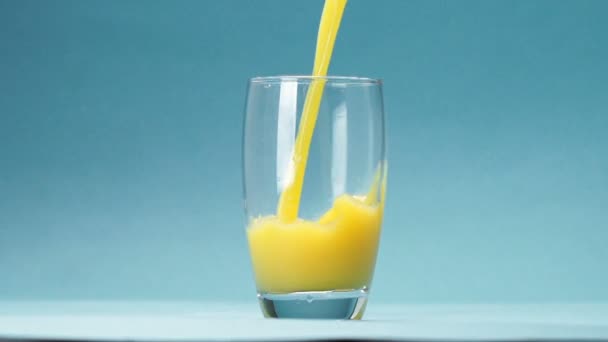 jus d'orange est versé dans un verre sur fond bleu 