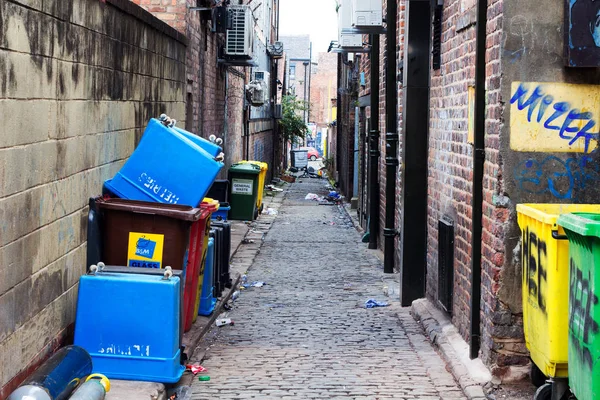 Mülltonnen in einer mit Müll übersäten Gasse Stockbild