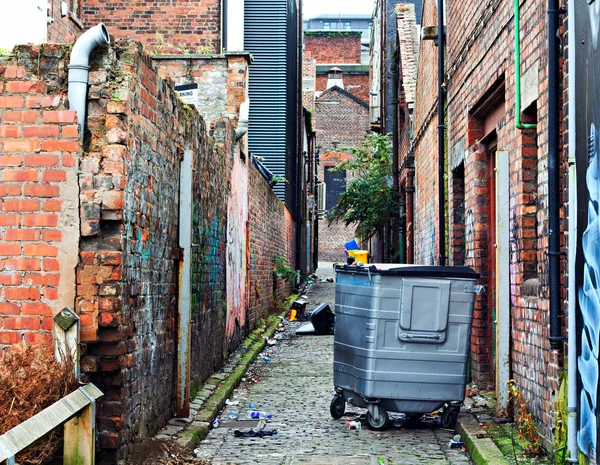 Mülltonnen in einer mit Müll übersäten Gasse Stockbild