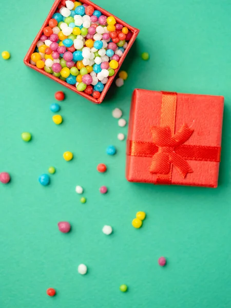 Caja de regalo roja llena de caramelos de colores sobre fondo verde — Foto de Stock