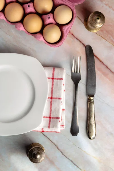 Breakfast with eggs, cutlery and white plate seen from above — Stock Photo, Image