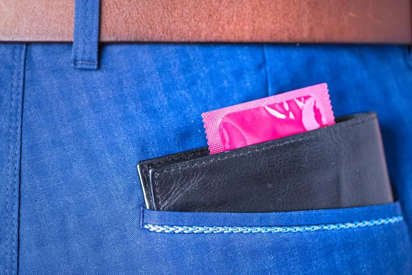 裤子口袋里钱包外面的红色避孕套包 — 图库照片