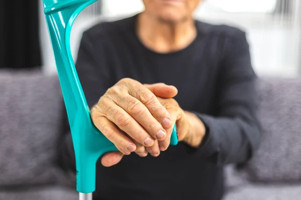 Elderly person standing with hands resting on medical walking stick — Stock Photo, Image