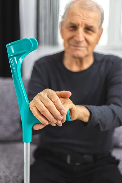 Personne âgée debout avec les mains reposant sur un bâton de marche médicale . — Photo