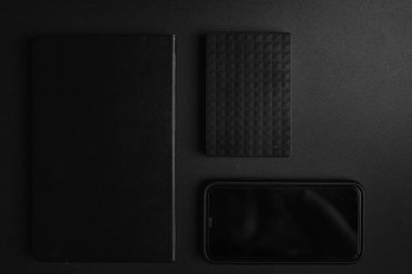 Mobil, hhd, siyah defterin üst görünümü siyah arkaplanda düzgünce düzenlenir ve ışık aşağıdan girer