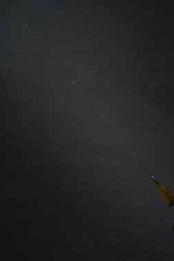 Şırıngadan çıkan sıvı sol alt köşeden siyah arka planda.