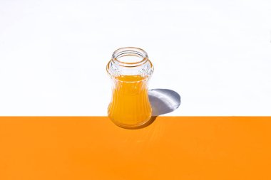 Beyaz ve turuncu zemin üzerinde portakal suyu olan yatay görüş camı iki yarım ve konteynır merkezli