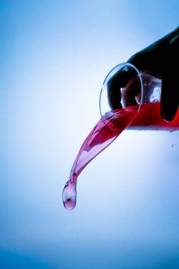 Sağ üst köşesinde mavi bir arka planda şarap lekesi olan plastik bir bardak tutuyordu.
