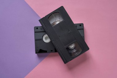 Çekici VHS video kasetleri pembe ve mor bir arkaplanda. Asgari retro kavramı