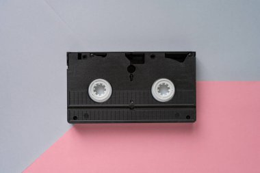 Pembe gri pastel arka planda video kaset. Retro tarzı, pop kültürü, minimalizm, üst görünüm
