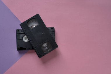 Çekici VHS video kasetleri pembe ve mor bir arkaplanda. Asgari retro kavramı