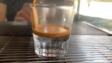 Bir kahve makinesinin ya da kahve makinesinin yakın çekiminde pişmiş sıcak kahvenin, feribotlu, 4k, 3840x2160 aromatik içeceği, cam bardağa dökülür.