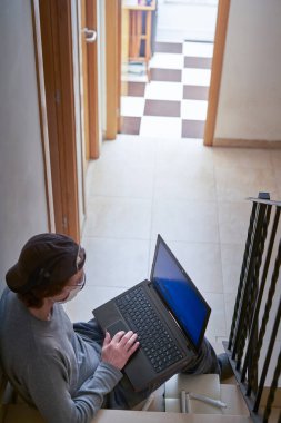 Adam çalışıyor ya da evde laptopla ve sağlık maskesiyle merdivenlerde çalışıyor. Evde kal.