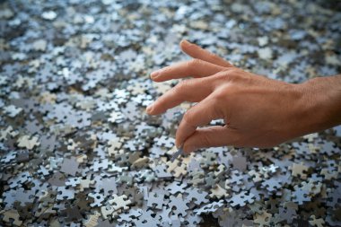 El yapboz parçalarını bir araya toplar, evde kalır.