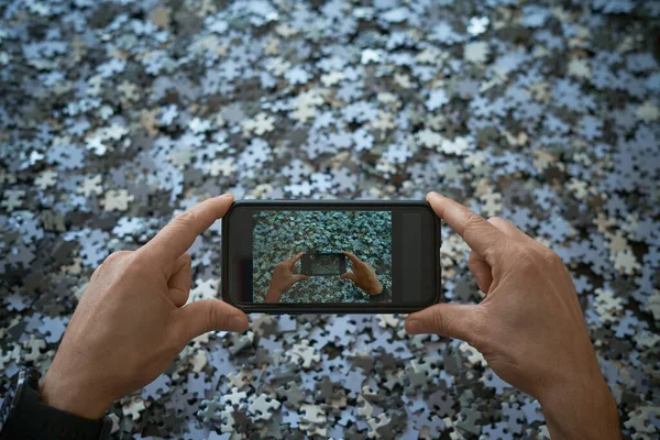 Person photographs with mobile phone a lot of puzzle pieces, stay at home