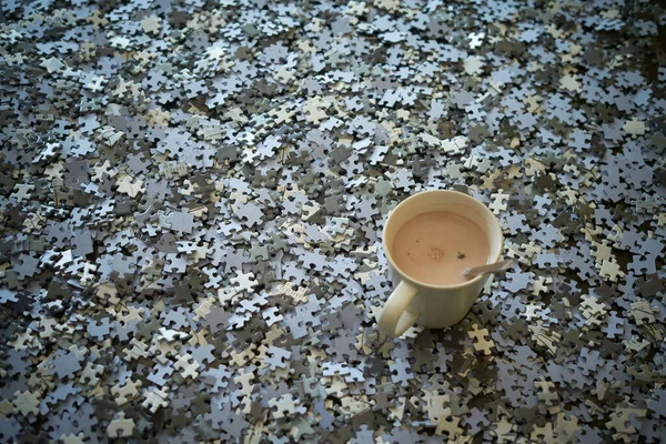 Bir fincan kahve ve yapboz parçaları bir arada. Evde kal.