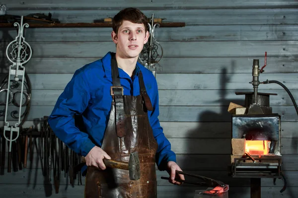 Jovem homem musculoso trabalhando em um ferreiro com metal — Fotografia de Stock