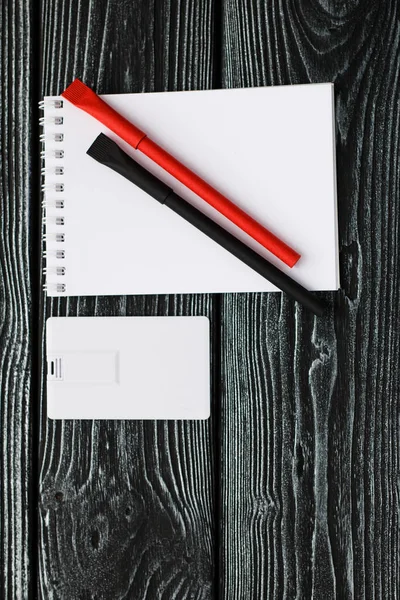 Notebook, red, beige, black penon dark wooden background — Stock Photo, Image