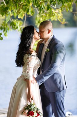 Gelin ve damat bir park kissing.couple yeni evli gelin ve damat doğa yeşil orman bir düğünde fotoğraf portre öpüşme.