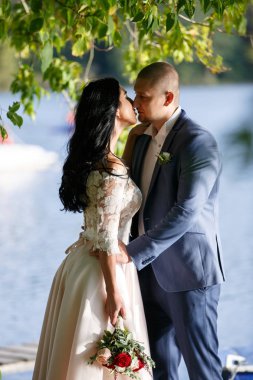 Gelin ve damat bir park kissing.couple yeni evli gelin ve damat doğa yeşil orman bir düğünde fotoğraf portre öpüşme.