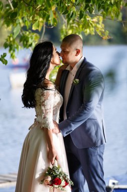 Gelin ve damat bir park kissing.couple yeni evli gelin ve damat doğa yeşil orman bir düğünde fotoğraf portre öpüşme.