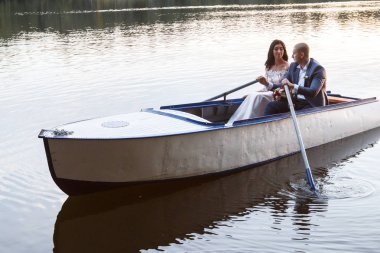 gün batımında gölde botla güzel genç bir çift. iki kişi. kadın ve erkek