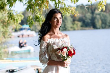 Gün batımında ormandaki bir buket ile genç güzel bir gelin portresi.