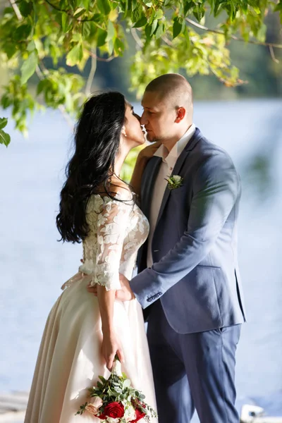 Novia y novio en un parque kissing.couple recién casados novia y novio en una boda en la naturaleza verde bosque están besando foto retrato . — Foto de Stock