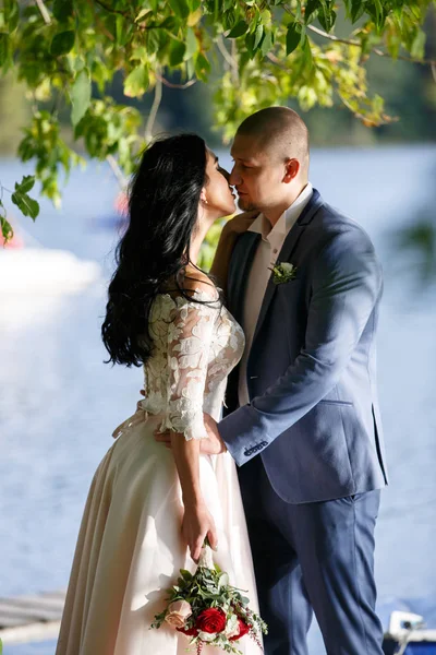 Novia y novio en un parque kissing.couple recién casados novia y novio en una boda en la naturaleza verde bosque están besando foto retrato . — Foto de Stock