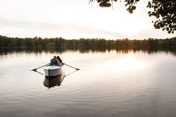 Belo jovem casal de barco no lago ao pôr-do-sol. Duas pessoas. mulher e homem — Fotografia de Stock