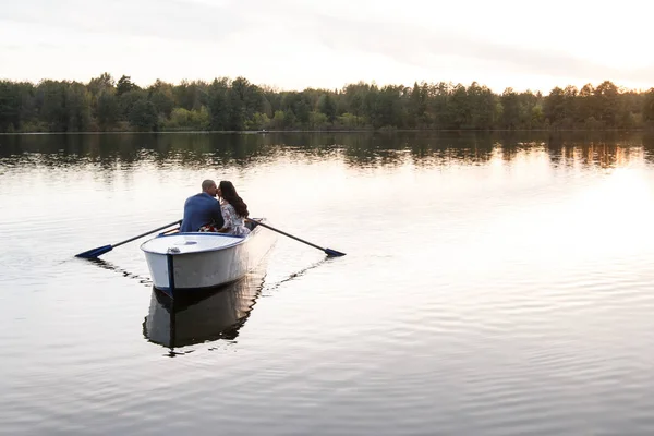 美丽的年轻夫妇在湖上划船日落。两个人。女人和男人 — 图库照片