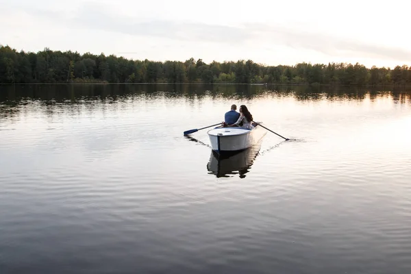 Beautiful young couple boating on the lake at sunset. two people. woman and man — Stock Photo, Image