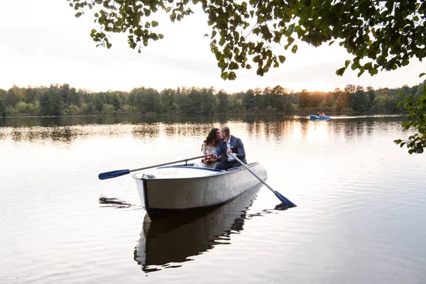 Belo jovem casal de barco no lago ao pôr-do-sol. Duas pessoas. mulher e homem — Fotografia de Stock