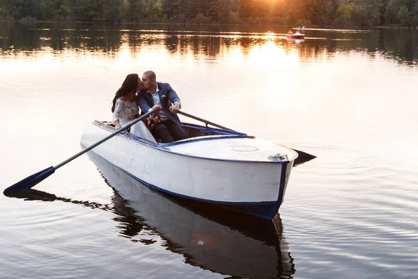 Belo jovem casal de barco no lago ao pôr-do-sol. Duas pessoas. mulher e homem — Fotografia de Stock