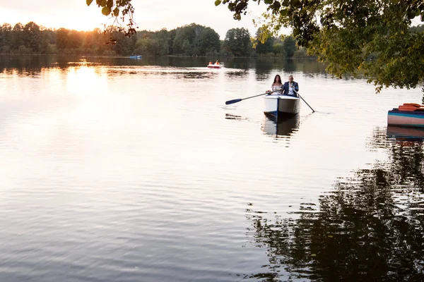 Belo jovem casal de barco no lago ao pôr-do-sol. Duas pessoas. mulher e homem — Fotografia de Stock
