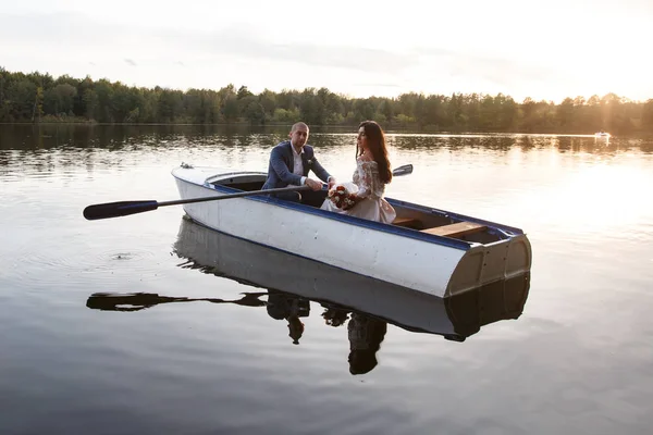 Belo jovem casal de barco no lago ao pôr-do-sol. Duas pessoas. mulher e homem — Fotografia de Stock