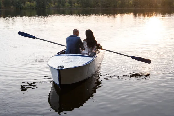 Belo jovem casal de barco no lago ao pôr-do-sol. Duas pessoas. mulher e homem — Fotografia de Stock