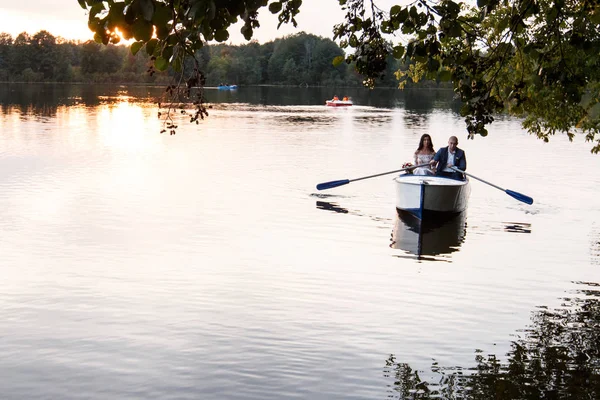 Belo jovem casal de barco no lago ao pôr-do-sol. Duas pessoas. mulher e homem — Fotografia de Stock