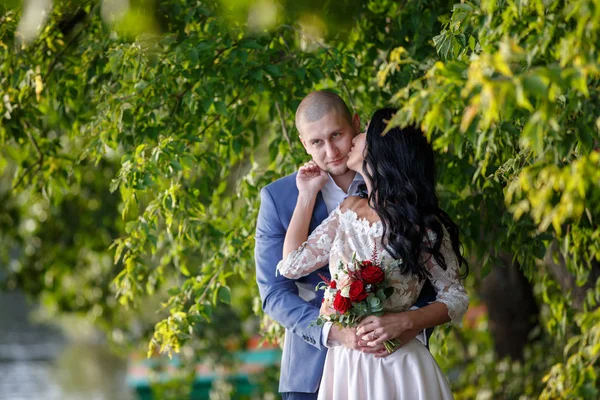 Novia y novio en un parque kissing.couple recién casados novia y novio en una boda en la naturaleza verde bosque están besando foto retrato . — Foto de Stock