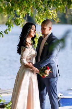 Yeni evli bir çift portreleri. Düğün çifti sipariş arka plan üzerinde duruyor. Mutlu aşıklar.