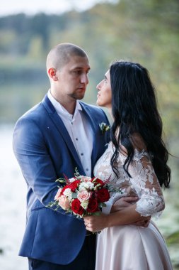 Gelin ve damat gülümseyen ve birbirine bakarak. Gelin buketi tutuyor. Köyde düğün yürüyüş.