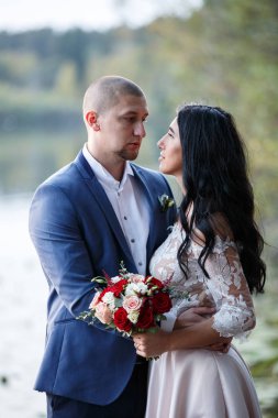 Gelin ve damat gülümseyen ve birbirine bakarak. Gelin buketi tutuyor. Köyde düğün yürüyüş.