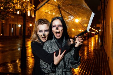 İki genç ve güzel kadın Cadılar Bayramı akşam sokakta yürüme makyaj