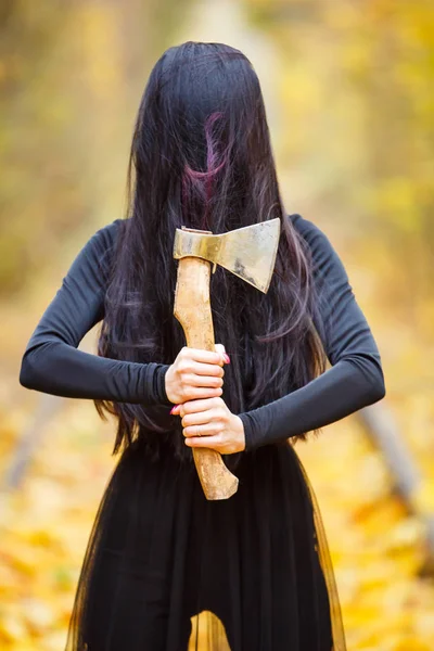 Belle fille avec une grosse hache massive dans son heand. Maquillage créatif idée folle conceptuelle pour Halloween soirée. Costume de carnaval de cauchemar, peinture d'art corporel. Photo professionnelle rapprochée — Photo