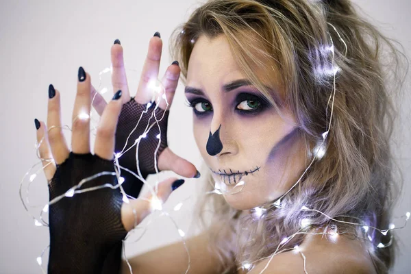 Attractive woman with sugar skull make-up  dolding burning garlands in hands — Stock Photo, Image