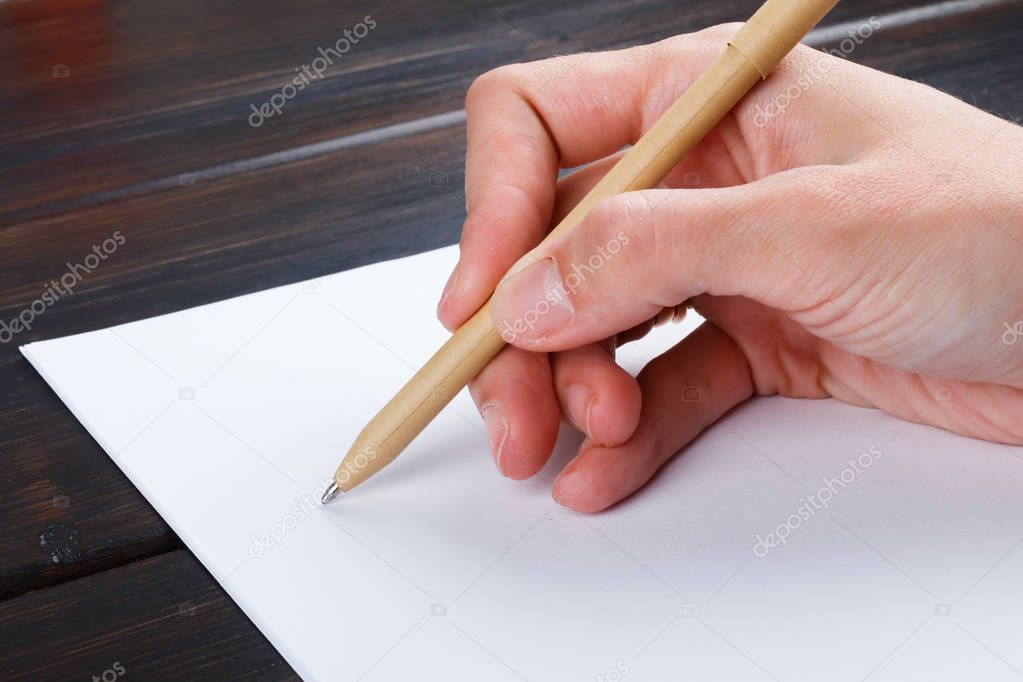 Hand is writing on a white list of paper with a pen composition. mock up design