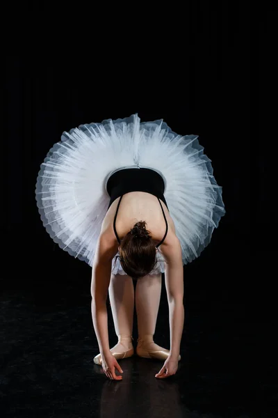 Ragazza ballerina posa ed esecuzione di elementi di danza in luce scenica brillante su uno sfondo nero — Foto Stock