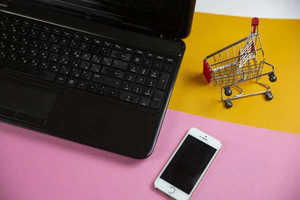 Computer Met Een Klein Winkelwagentje Een Gele Achtergrond — Stockfoto